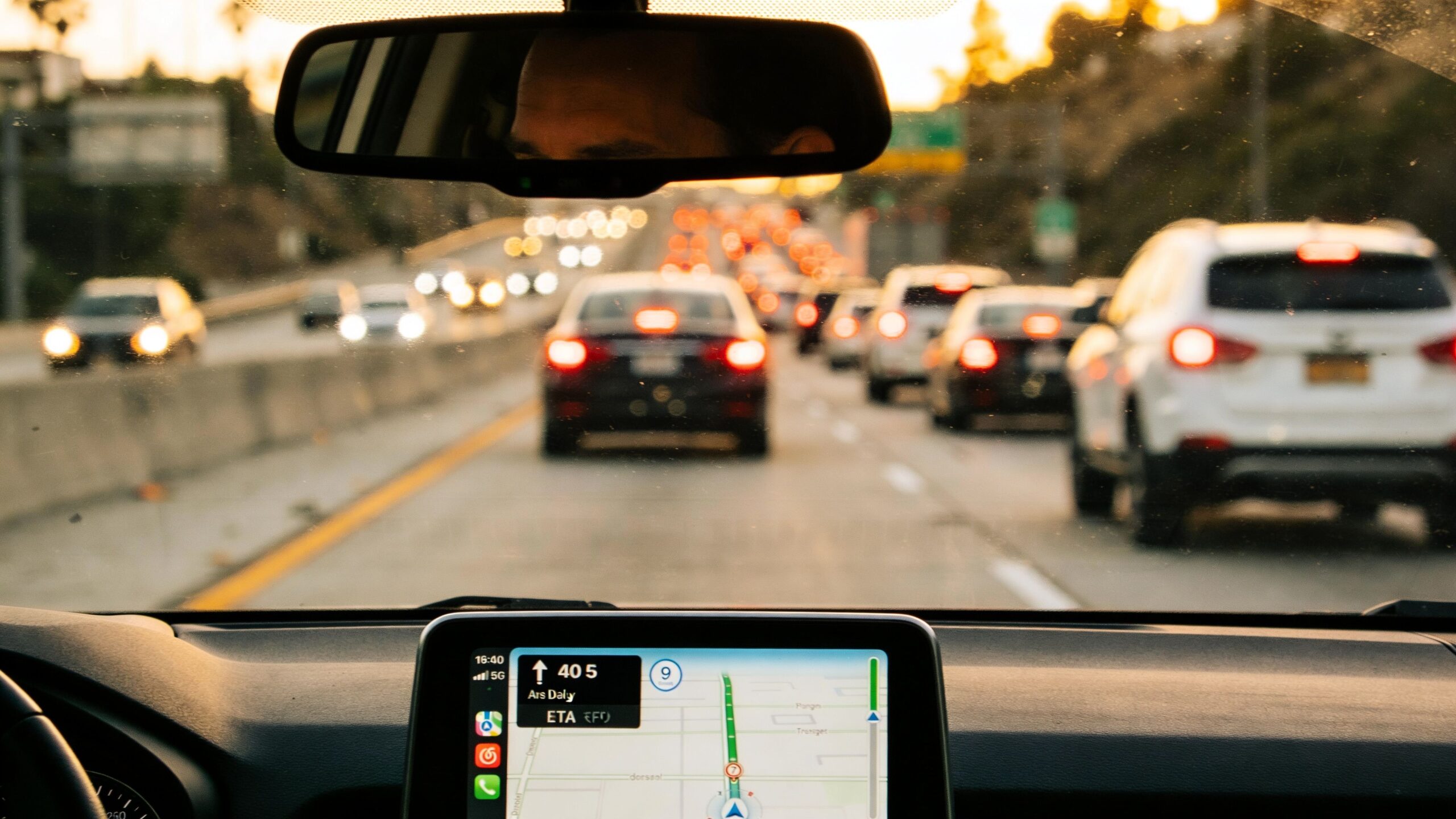 Your Guide to Transportation to Los Angeles 2 Rides On Time A view from inside a car driving on a congested Los Angeles highway at sunset with navigation active.